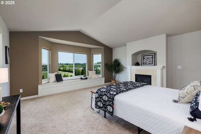 carpeted bedroom featuring a tiled fireplace, baseboards, and lofted ceiling