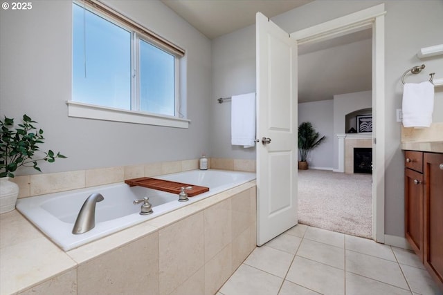full bathroom with a tiled fireplace, tile patterned floors, vanity, and a garden tub