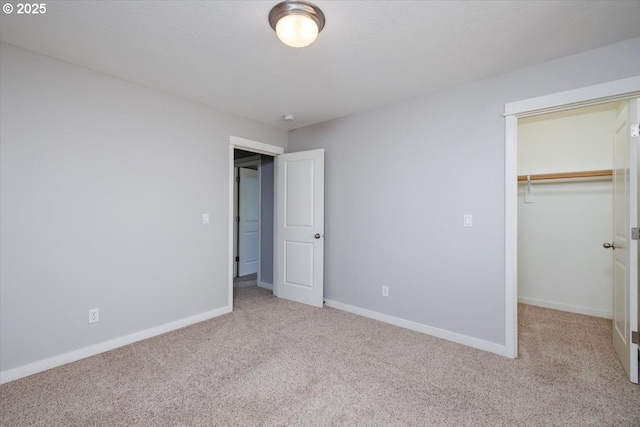 unfurnished bedroom featuring carpet floors, baseboards, a closet, and a spacious closet