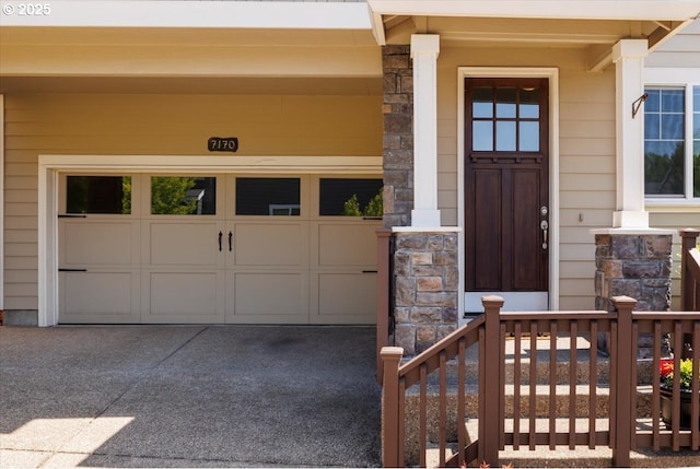 entrance to property featuring concrete driveway and stone siding