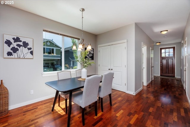 dining area with baseboards, an inviting chandelier, and dark wood-type flooring