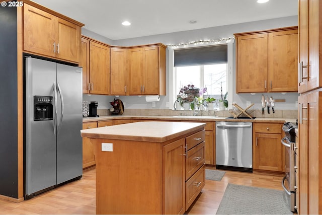 kitchen featuring sink, light wood-type flooring, a center island, and appliances with stainless steel finishes