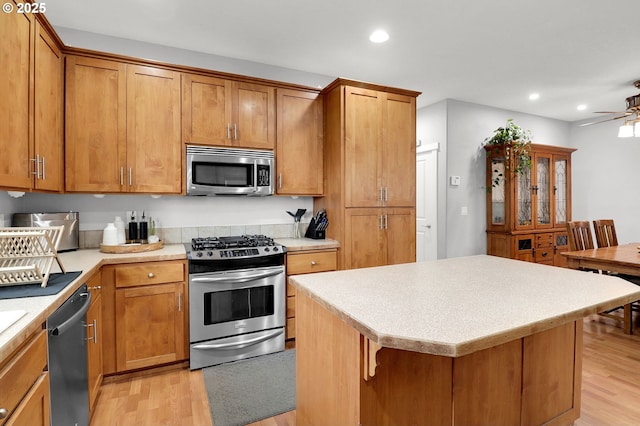 3730 Hemlock Pl SE, Albany, OR 97322 - kitchen featuring appliances with stainless steel finishes, light wood-style flooring, brown cabinetry, recessed lighting, and light countertops