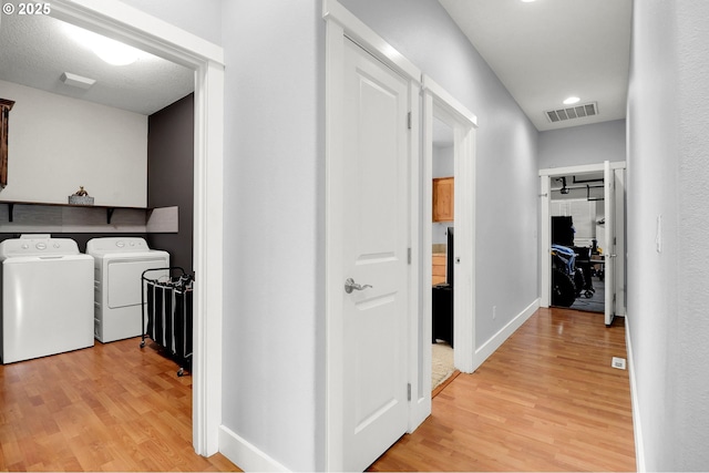 hall with washing machine and clothes dryer and light wood-type flooring