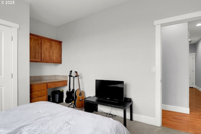 bedroom with built in desk and light hardwood / wood-style floors