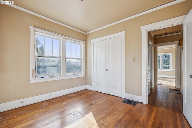 unfurnished bedroom with crown molding, wood-type flooring, and a closet