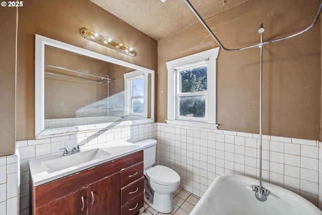 bathroom with toilet, tile walls, vanity, a bathtub, and tile patterned flooring