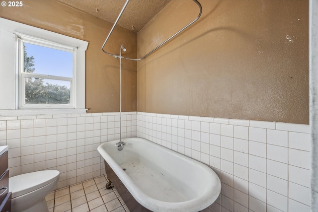 bathroom with tile walls, vanity, toilet, a bath, and tile patterned floors