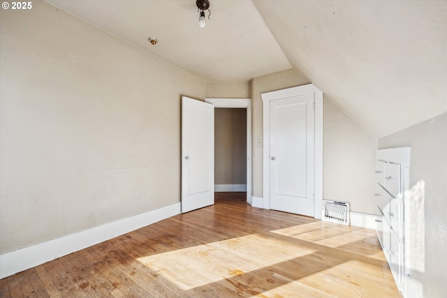 additional living space with hardwood / wood-style flooring and vaulted ceiling