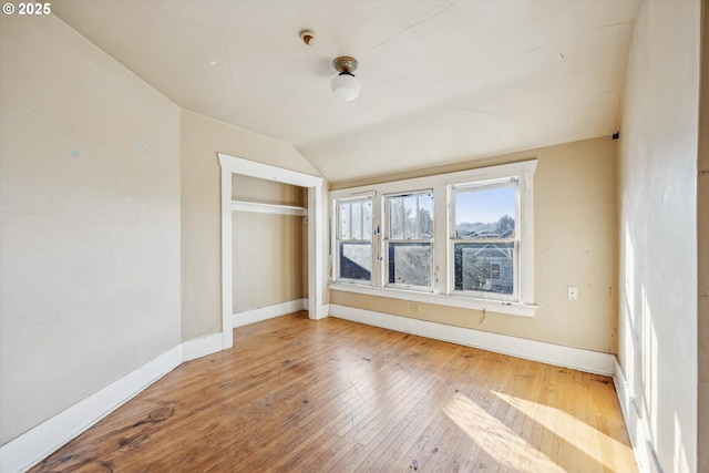 unfurnished bedroom with hardwood / wood-style flooring, vaulted ceiling, and a closet