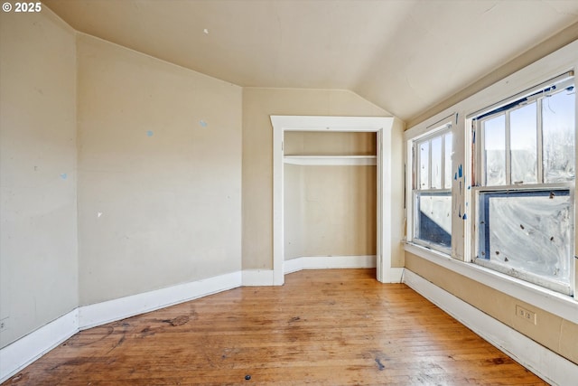 unfurnished bedroom with vaulted ceiling and light hardwood / wood-style floors