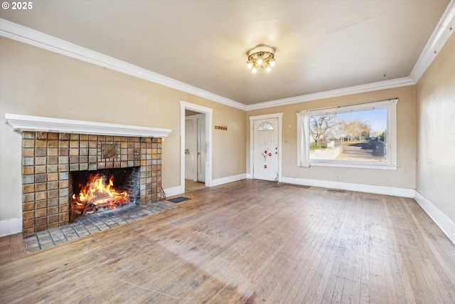 unfurnished living room with hardwood / wood-style flooring, ornamental molding, and a fireplace