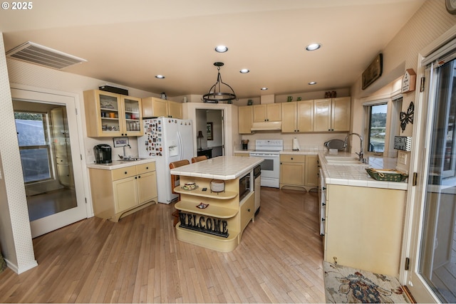 kitchen with sink, tile countertops, a center island, pendant lighting, and white appliances