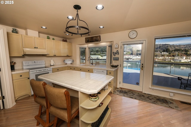 kitchen with sink, decorative light fixtures, light hardwood / wood-style flooring, tile counters, and white range with electric stovetop