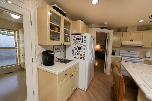 kitchen with light hardwood / wood-style flooring, sink, white appliances, and tile counters