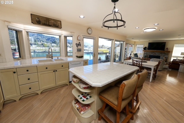 kitchen with white dishwasher, sink, pendant lighting, and tile countertops