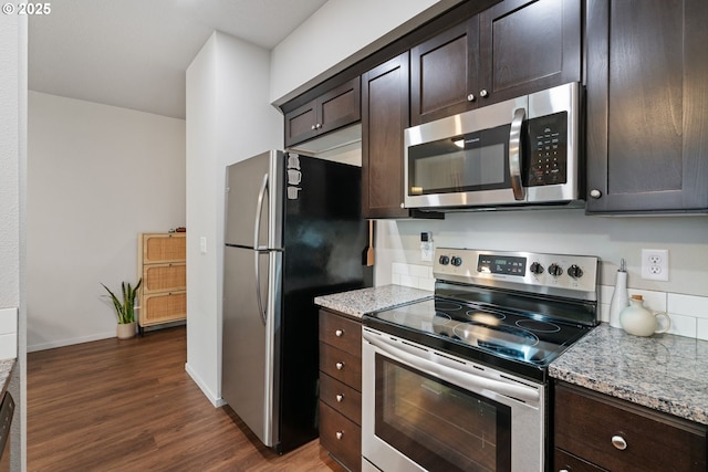 kitchen with dark brown cabinets, dark hardwood / wood-style flooring, stainless steel appliances, and light stone counters