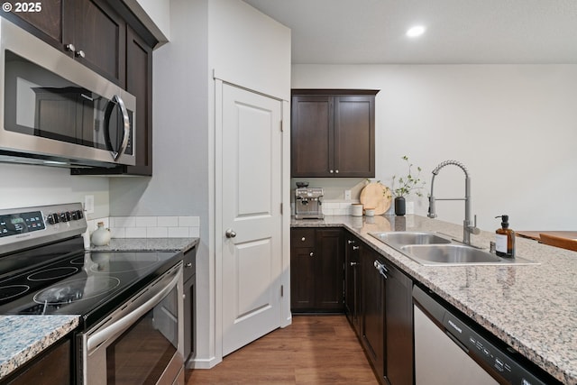 kitchen with dark brown cabinets, stainless steel appliances, hardwood / wood-style flooring, and sink