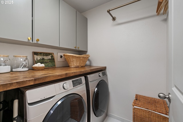 clothes washing area featuring washer and dryer and cabinets