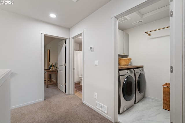 laundry room with cabinets, light colored carpet, and washer and clothes dryer