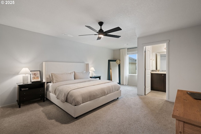 carpeted bedroom with a textured ceiling, ceiling fan, and ensuite bathroom