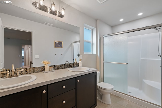 bathroom with backsplash, tile patterned floors, vanity, toilet, and a shower with shower door