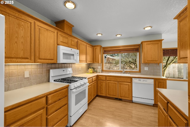 kitchen featuring white appliances, a healthy amount of sunlight, light hardwood / wood-style floors, and sink