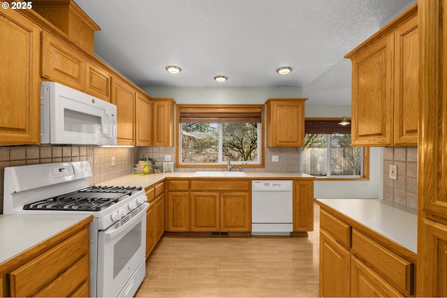 kitchen featuring backsplash, white appliances, sink, and light wood-type flooring