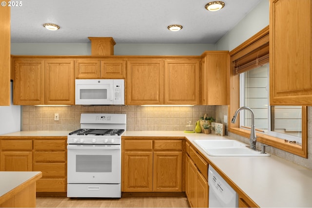 kitchen featuring sink, white appliances, light hardwood / wood-style floors, and backsplash