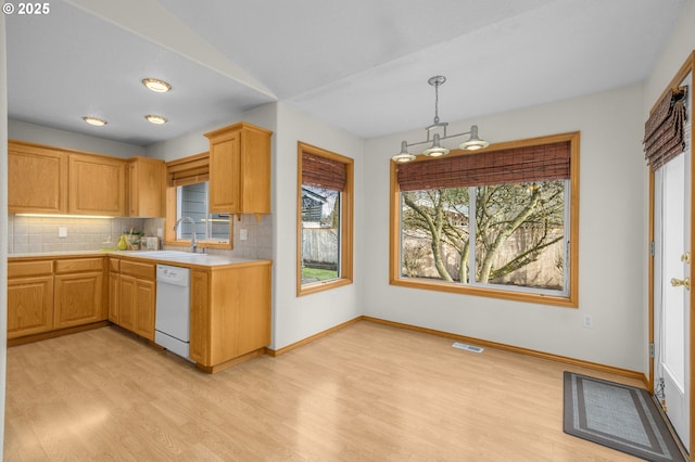 kitchen featuring light brown cabinetry, sink, decorative light fixtures, dishwasher, and backsplash