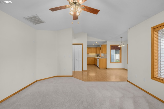 unfurnished living room with light colored carpet, lofted ceiling, and ceiling fan with notable chandelier