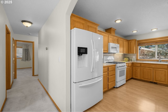 kitchen with white appliances, sink, decorative backsplash, and light wood-type flooring