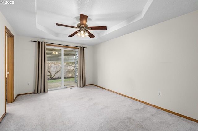 empty room with ceiling fan, a tray ceiling, light colored carpet, and a textured ceiling