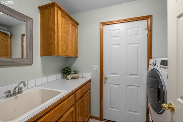 clothes washing area featuring washer / clothes dryer, cabinets, and sink