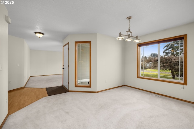 unfurnished room with light colored carpet, a textured ceiling, and a notable chandelier