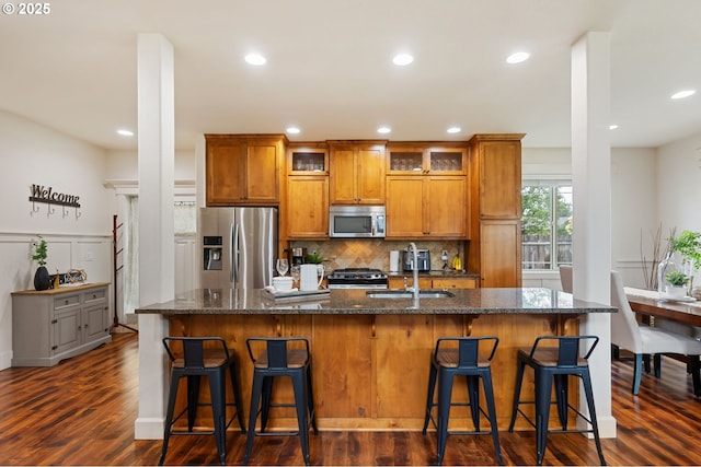 19144 Gentry Highlands Ln, Oregon City, OR 97045 - kitchen featuring stainless steel appliances, brown cabinets, a center island with sink, a sink, and backsplash