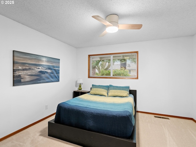 carpeted bedroom with ceiling fan and a textured ceiling