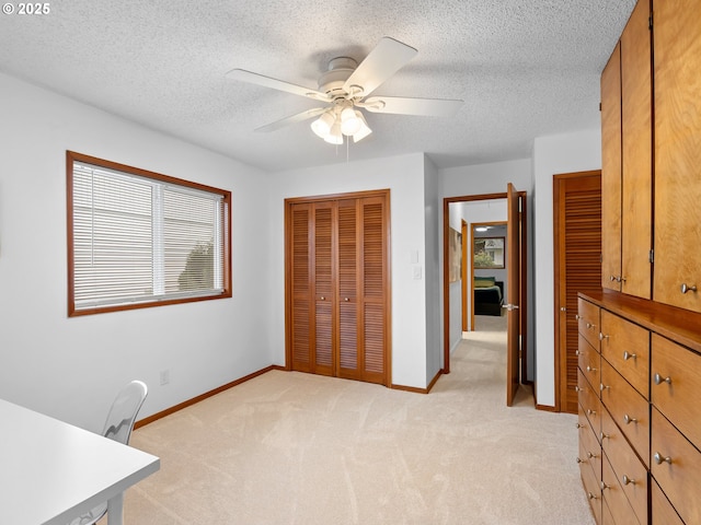 unfurnished office with a textured ceiling, light carpet, and ceiling fan