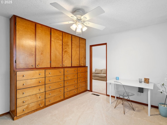 carpeted home office featuring a textured ceiling and ceiling fan