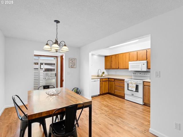 kitchen featuring white appliances, a textured ceiling, light hardwood / wood-style flooring, pendant lighting, and an inviting chandelier