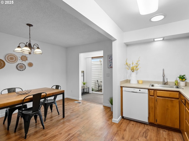 kitchen featuring hanging light fixtures, a notable chandelier, light hardwood / wood-style floors, white dishwasher, and sink