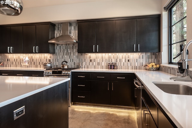 kitchen with wall chimney range hood, a sink, backsplash, and light countertops