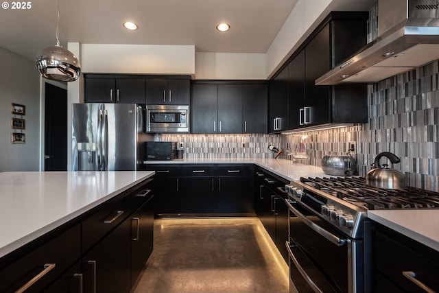 kitchen with stainless steel appliances, wall chimney range hood, dark cabinets, light countertops, and recessed lighting