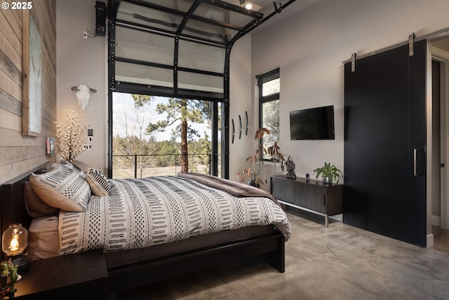 bedroom featuring a high ceiling, concrete flooring, and access to exterior