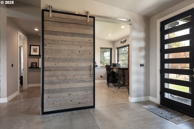 foyer entrance with finished concrete floors, a barn door, recessed lighting, and baseboards