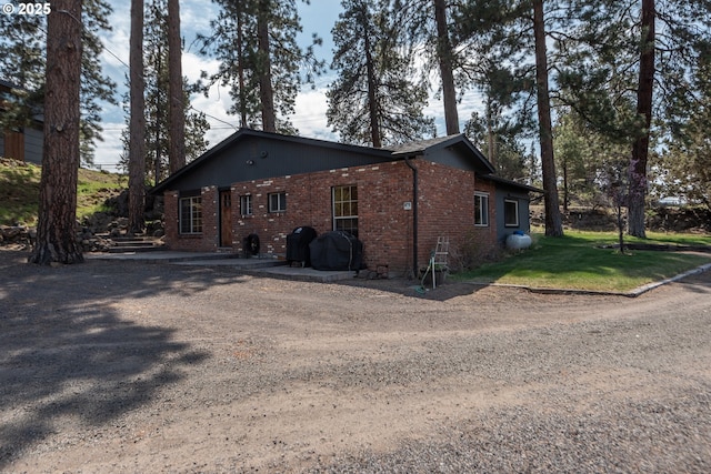 view of home's exterior with brick siding, a lawn, and driveway