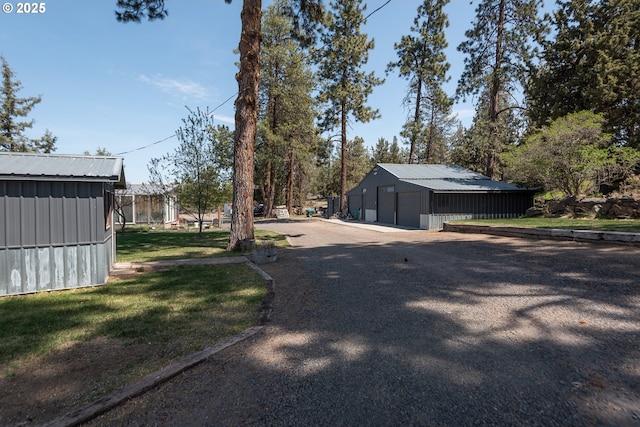 view of yard featuring a detached garage, an outdoor structure, and driveway