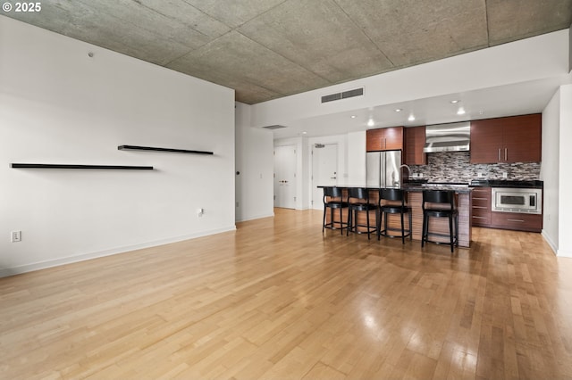 living area with baseboards, visible vents, and light wood finished floors