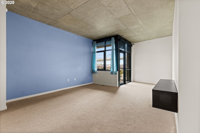 spare room featuring carpet flooring and baseboards