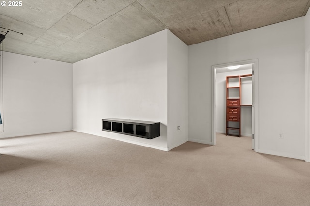 unfurnished living room featuring light colored carpet and baseboards